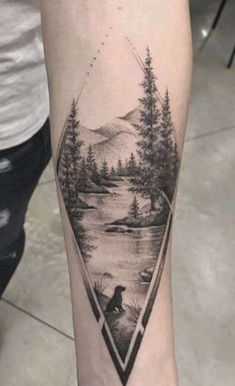 a person with a tattoo on their arm is standing in front of a lake and trees