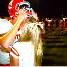 the football players are hugging each other on the sidelines at night, with lights in the background