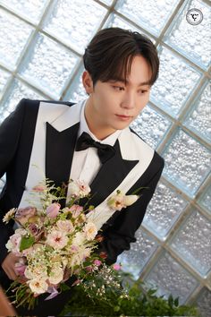 a man in a tuxedo holding a bouquet of flowers