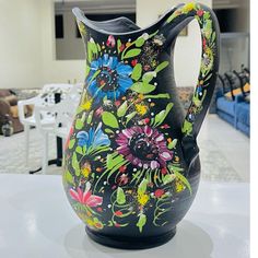 a black vase with colorful flowers painted on it