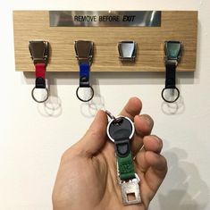 a person holding a key in front of four different keys on a wall mounted to a coat rack