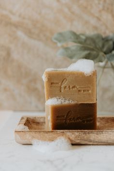 two soap bars sitting on top of a wooden tray next to a potted plant