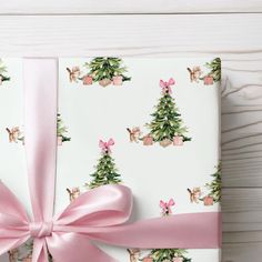 a present wrapped in pink ribbon and decorated with deers, pine trees and bows