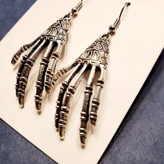 Skeleton Hands Halloween Dangling Fashion Alloy Earrings With Silver Hooks. Length 2" Width 3/4" Nickel-free Punk Halloween Earrings, Nickel-free Punk Earrings For Halloween, Punk Nickel-free Earrings For Halloween, Punk Style Nickel Free Earrings For Halloween, Edgy Adjustable Earrings For Halloween, Witchy Metal Earrings For Halloween, Edgy Drop Earrings For Halloween, Witchy Metal Halloween Earrings, Edgy Halloween Drop Earrings