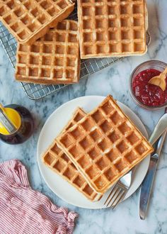 three waffles sitting on top of a white plate next to a bowl of fruit