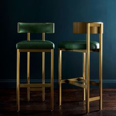 two green barstools in front of a dark blue wall and wooden flooring