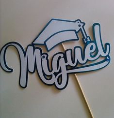 a cake topper that says miguel with a graduation cap and tassel on it