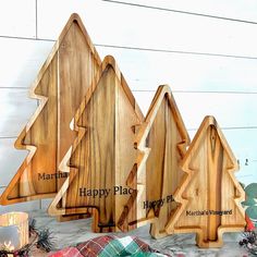 three wooden christmas trees with happy place written on them and plaid blanket next to it