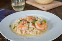 shrimp and grits on a white plate with a glass of water in the background