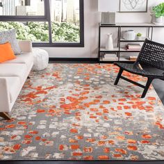 an orange and gray rug in a living room next to a white couch with black chairs