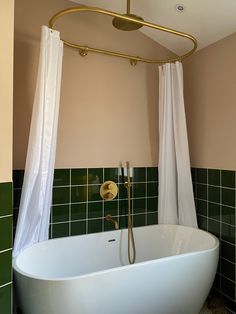 a bathtub in a bathroom with green tiles and gold fixtures on the shower head