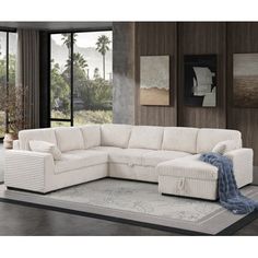 a white sectional couch sitting on top of a rug in front of a large window