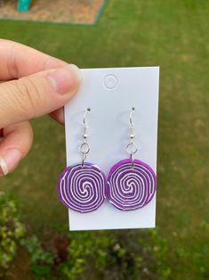 a pair of purple and white earrings with swirl designs on them in front of a green field