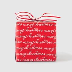 a red christmas present wrapped in white and red paper with a ribbon on it's top