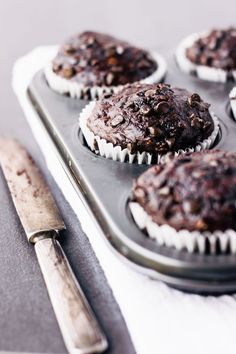 chocolate muffins sitting on top of a pan next to a knife