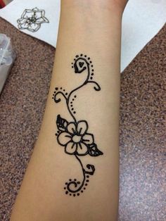 a woman's arm with a black and white flower tattoo on her left wrist