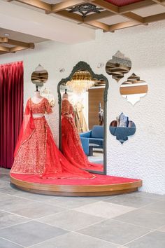 a mannequin dressed in an orange gown is standing next to a large mirror