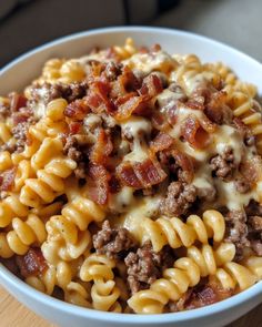 a white bowl filled with macaroni and cheese covered in ground beef, bacon and melted cheese