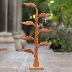 a wooden tree with earrings hanging from it's branches on a table in front of some steps