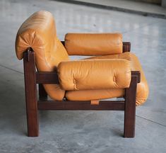 a brown leather chair sitting on top of a cement floor next to a wooden frame