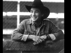 a black and white photo of a man wearing a cowboy hat with his arms crossed