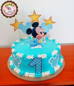 a blue birthday cake with a mickey mouse topper on it's side and stars in the background