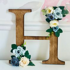 a wooden letter decorated with flowers and greenery