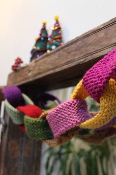 several knitted items hanging from a wooden shelf