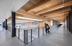 two people are walking up and down the stairs in an open area with wooden ceilinging