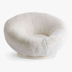 a white chair that is made out of sheepskin and has a round cushion on it