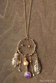 a gold plated dream catcher necklace with beads and feathers hanging from it's chain