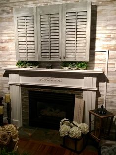 a fireplace with shutters and flowers in front of it