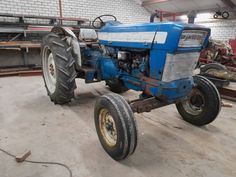 an old blue tractor parked in a garage