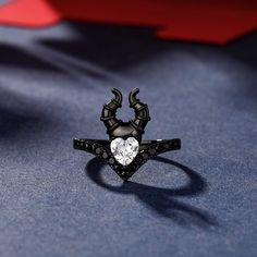 We all get that dark feeling, especially when we're hardened by life. Take inspiration from a fairy tale story and find the courage inside you to rise above adversity. Let this glorious ring serve as a reminder for you to unleash your inner hero. This ring is fashioned in sterling silver with black plating. The center part is a heart cut white stone with two evil horns. Your look isn't complete without this fabulous ring.Carat Weight: 0.5 ctStone Size: 5*5 mmStone Type: Jeulia® StoneNumber of St Fantasy Style Black Ring For Gift, Black Fantasy Style Rings As Gift, Black Fantasy Rings As Gift, Fantasy Rings For Halloween Gift, Spiritual Black Jewelry For Promise, Black Symbolic Jewelry For Promise, Black Sterling Silver Fantasy Jewelry, Symbolic Black Promise Ring, Symbolic Black Jewelry For Promise