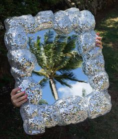 a woman is holding up a mirror that has been made to look like a palm tree