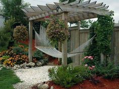 a hammock in the middle of a garden with rocks and plants around it