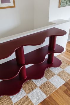 a red shelf sitting on top of a hard wood floor next to a white wall