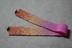 two pink and gold bracelets sitting next to each other on a gray surface,