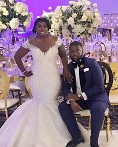 the bride and groom pose for a photo in front of their wedding reception table with floral centerpieces