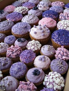 a box filled with lots of purple and pink cupcakes