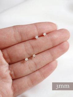 Tiny star stud earrings in 3 sizes, micro, tiny and little.  Sold as a PAIR of the same size (choose options above).A sweet little sparkle for the modern romantic.  Hand set faceted cubic zirconia hearts subtly catch the light.  Hardware has been tumble polished for hours to achieve a satin finish, butterfly backings.  Packaged in a beautiful gift box.Perfect for standard lobe piercings and make great stacking pieces for 2nd and 3rd piercings (shown worn, paired with our micro puffed heart studs Gold Star Earrings Studs, Tiny Dainty Cubic Zirconia Piercings, Minimalist Star-shaped Cubic Zirconia Jewelry, 3rd Piercings, Small Earrings Gold, Lobe Piercings, Gold Star Earrings, Second Piercing, Star Stud Earrings