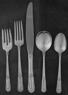 five silverware pieces including forks, knives and spoons on a black surface with white writing