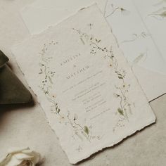 the wedding stationery is laid out on the floor next to some flowers and leaves