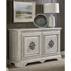 a white dresser with two drawers and a painting on the wall