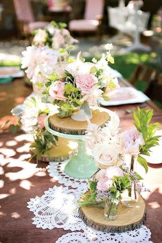 three tiered cake stands with flowers and greenery on the top, along with lace doily