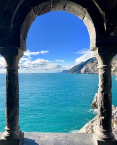 an arch overlooking the water and mountains