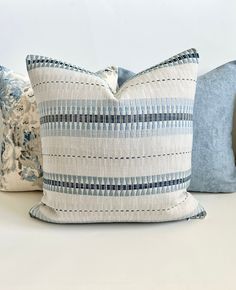 three blue and white pillows sitting on top of a bed