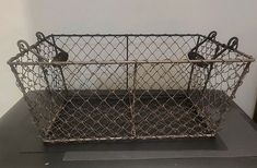 a metal basket sitting on top of a black table next to a white and gray wall