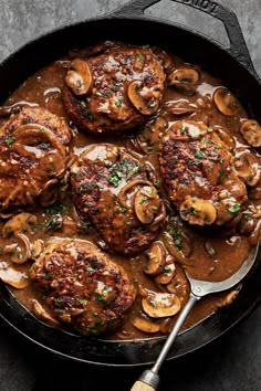 a skillet filled with meat covered in mushroom gravy and topped with mushrooms