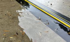 a yellow and black water hose laying on the ground next to it's reflection